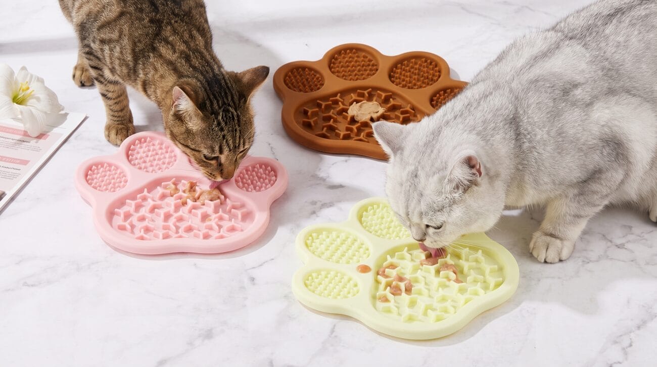 Two cats licking, a civet and a silver taper.